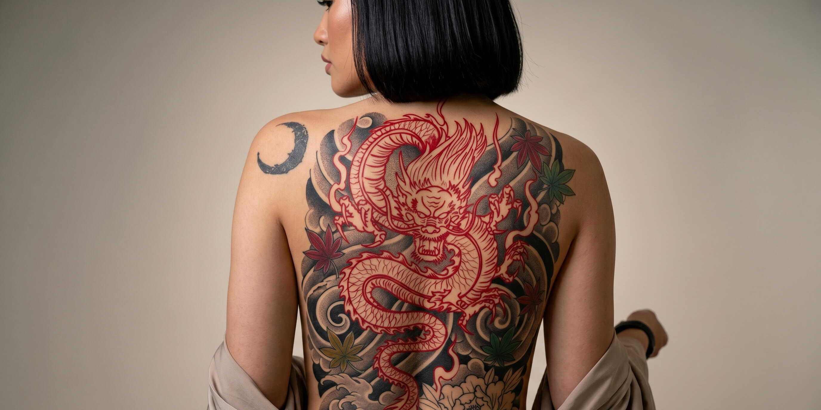 Stunning full Japanese backpiece tattoo featuring a vibrant red dragon weaving through dark charcoal clouds and cherry blossoms